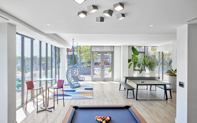 room with  pool table and chairs and a large glass door J Malden Center apts Malden MA 