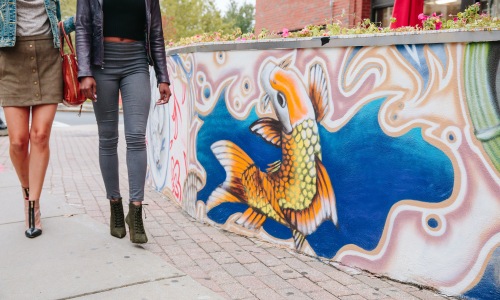 Walkable Location Two women walking on sidewalk past a colorful koi fish mural