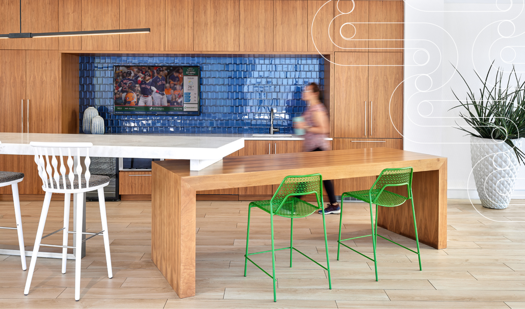 Modern Amenities in Malden a person walking by demonstration kitchen with a tv and chairs J Malden Center apts Malden MA