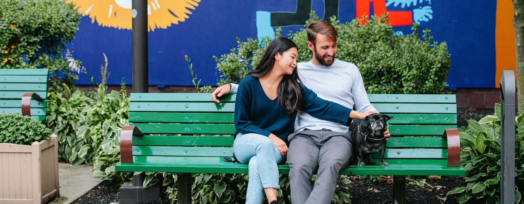 a couple sitting on a bench with their dog